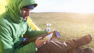 how to charge phones when camping: man charging phone using solar charger