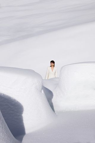 Lady in white jacket stood behind snow mounds