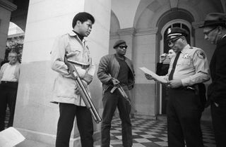 Two members of the Black Panther Party are met on the steps of the State Capitol in Sacramento, May 2, 1967, by Police Lt. Ernest Holloway, who informs them they will be allowed to keep their weapons as long as they cause no trouble and do not disturb the peace. Earlier several members had invaded the Assembly chambers and had their guns taken away.