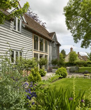 A beautiful oak frame home with considered landscaping with a lawn and gravelled area and large planting beds