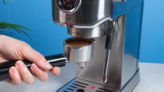 The Casabrews 5418Pro espresso machine in stainless steel with a steam wand on the right side and three buttons on the front of the machine and a pressure gauge underneath