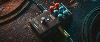 MXR MB301 Bass Synth: the dark gray bass pedal has light blue and orange dials and is photographed here against a distressed wooden background.