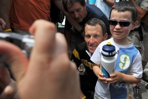 Lance Armstrong shows his soft side as he spends some time posing with kids waiting next to Astana's team bus.
