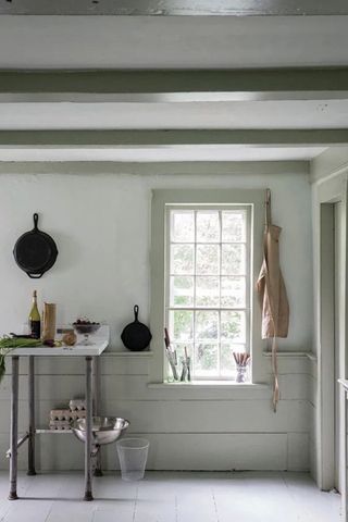 Period room with small prep table with back cast irons on the wall and taupe window trims