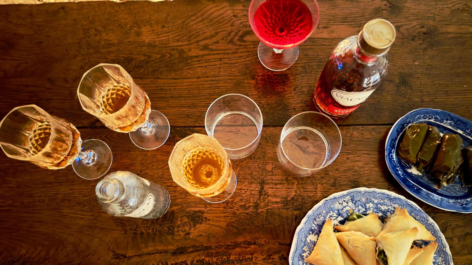 Glasses of sherry and cocktails and bowls of filo parcels and dolma on a wooden table