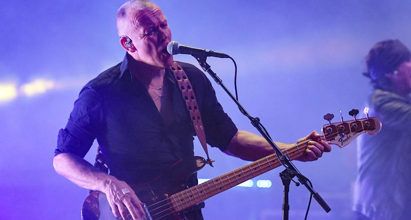 Charlie Jones of the Cult plays a see-through bass guitar live onstage and sings into the mic.