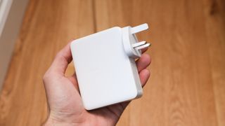 Belkin BoostCharge Pro 140W 4-Port GaN Wall Charger held in a hand above a wooden floor