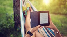 woman lying in hammock holding an ereader