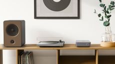 WiiM Amp in lifestyle setting with speaker and turntable on a desktop
