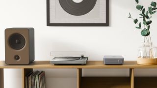 WiiM Amp in lifestyle setting with speaker and turntable on a desktop