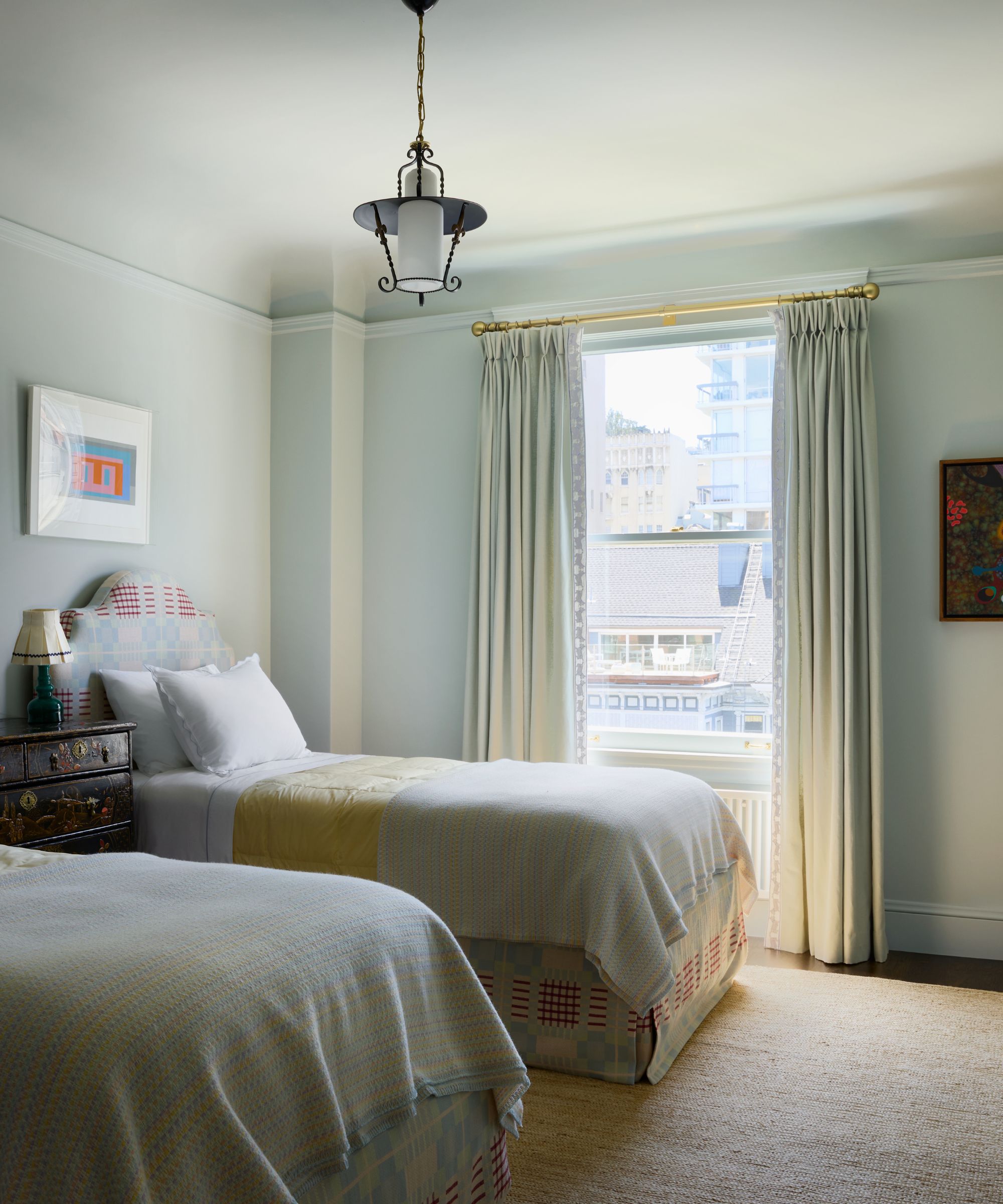 a pale blue kids bedroom with upholstered twin beds and a sweet vintage pendant