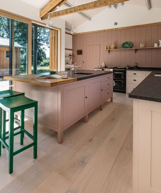 pink kitchen with wood accents and green stools
