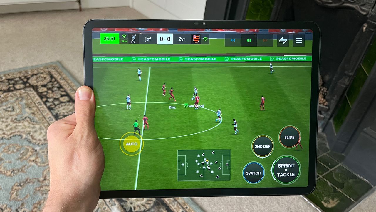 Hand holding Huion Kamvas Slate 13 while playing FIFA Mobile