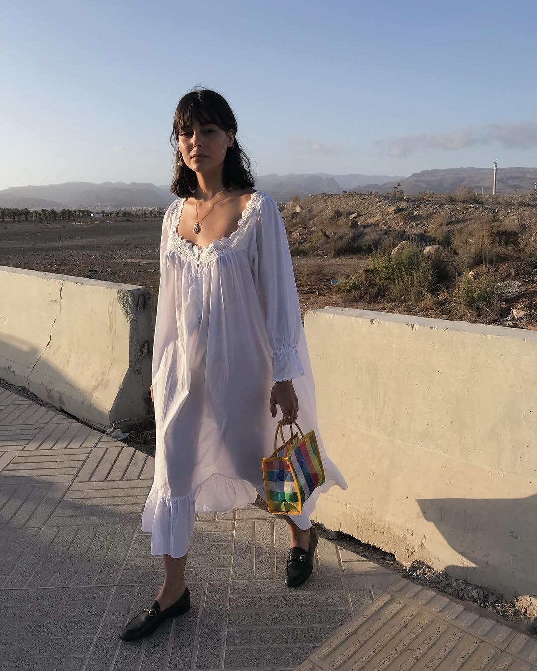 Influencer wearing white summer dress and mesh market tote.