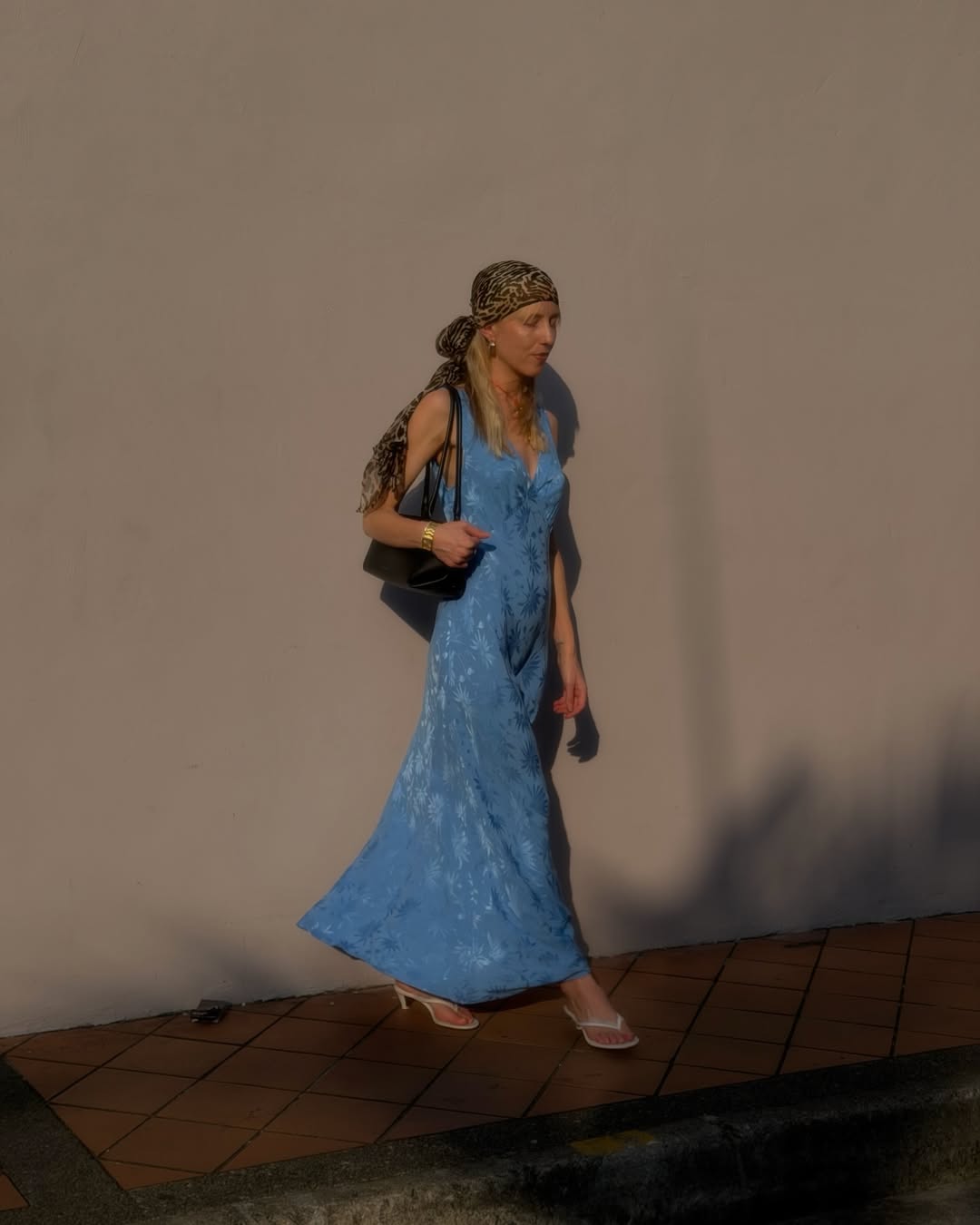 Influencer Alice Zielasko wearing a blue satin floral dress, thong sandals and head scarf.