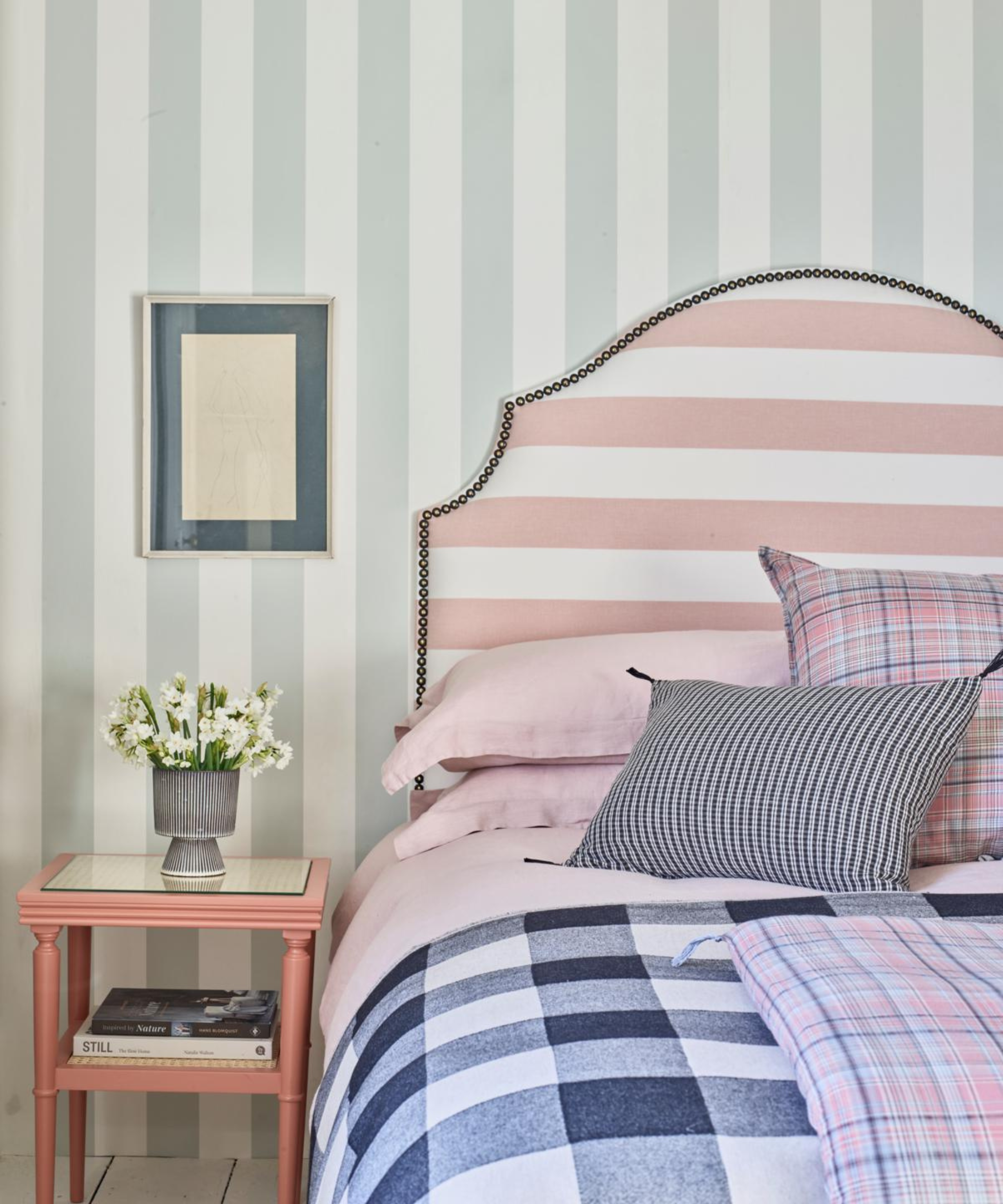 a bedroom with striped wallpaper, a striped headboard, and checker printed bedding