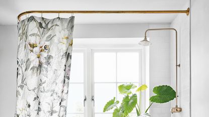 White bathroom with floral shower curtain and brass fixtures
