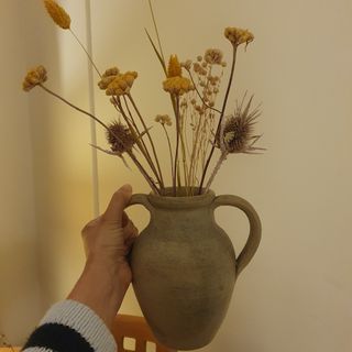 A vase with dried flowers without a flower frog