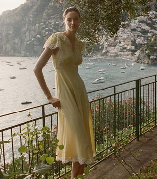 seorang model mengenakan gaun kuning dengan hiasan renda putih