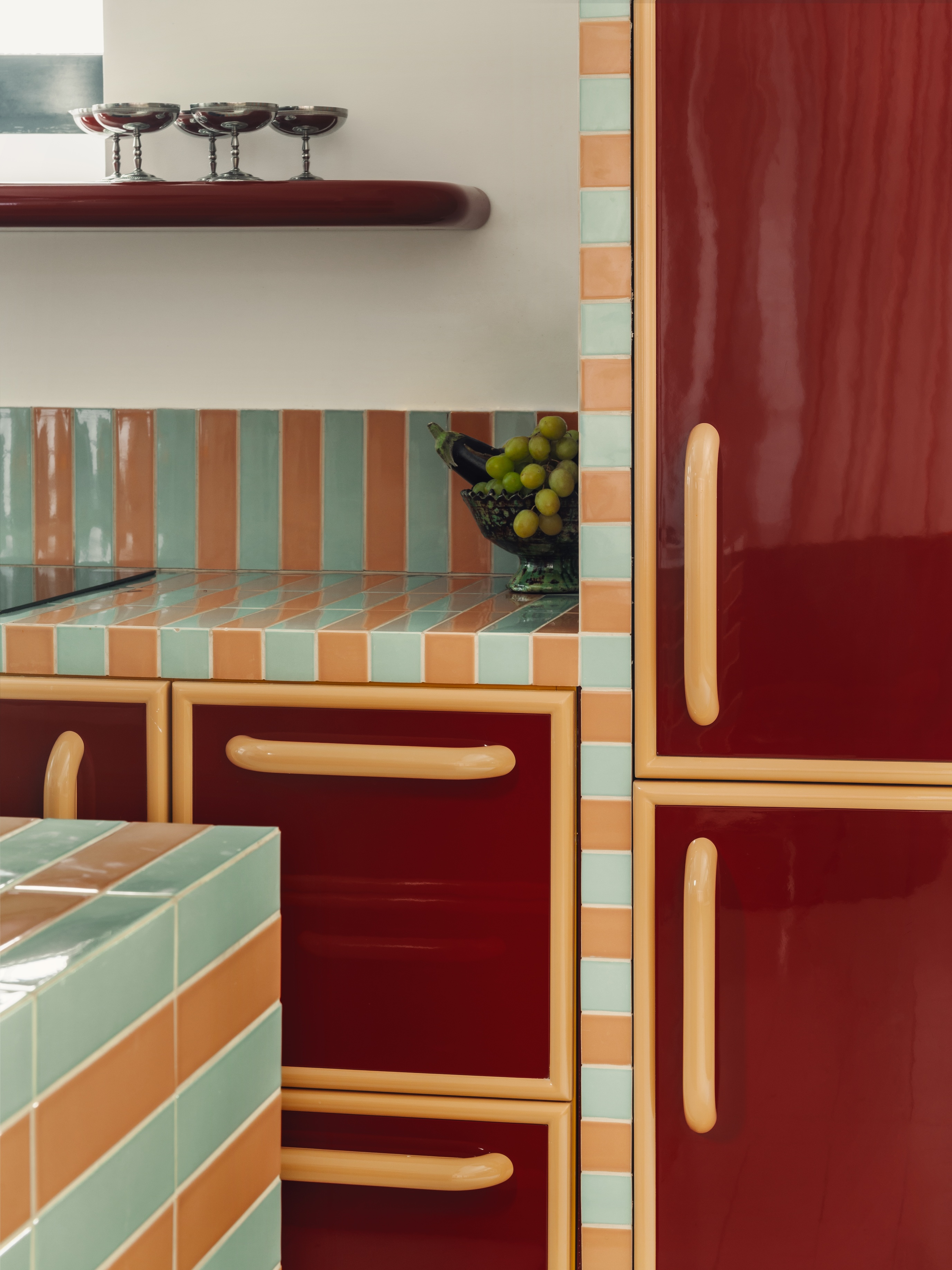 A colorful kitchen counter with lacquered millwork and colorful tiles