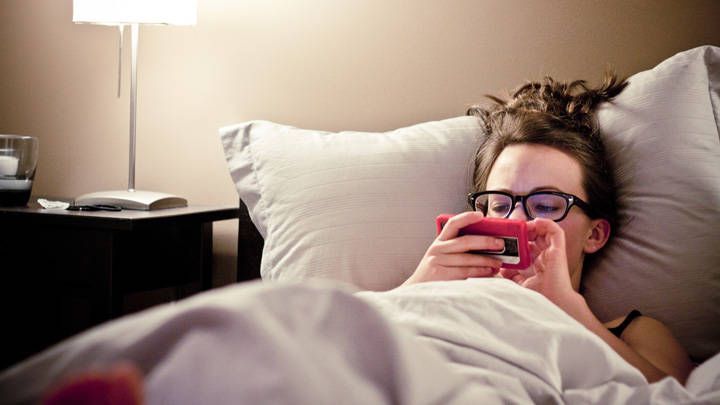 women in bed on phone