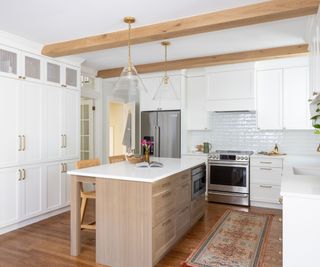 a white and wood kitchen with two statement gold and glass pendant lights over the island