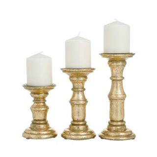 Three gold candlesticks with white candles on them