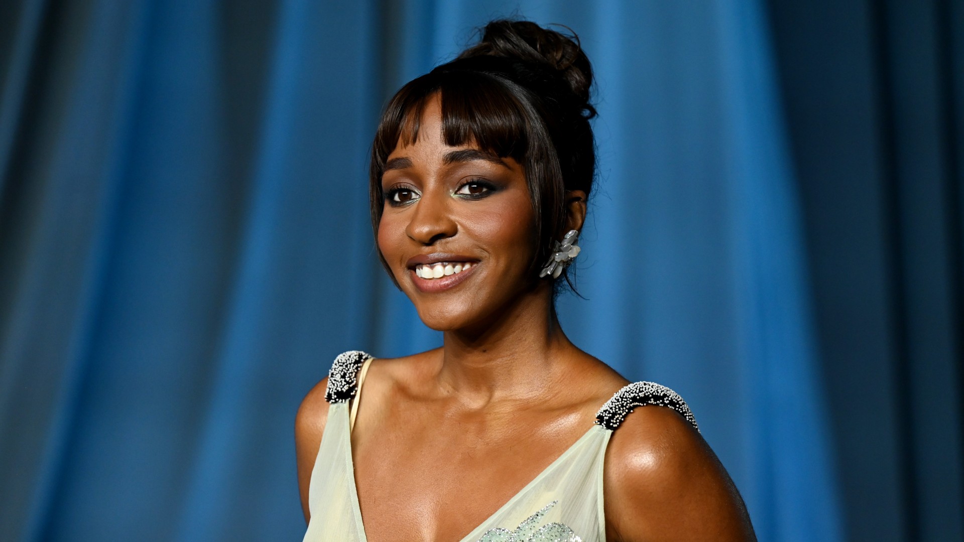 a black woman with dark hair posing on a red carpet in front of a blue background