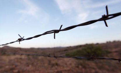 A barbed wire fence marks the border of the United States and Mexico near Sasabe, Arizona.