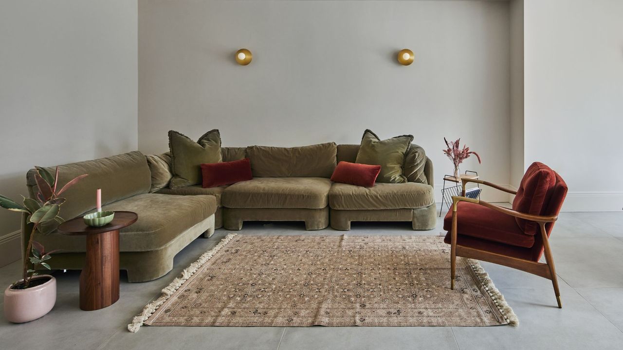 A clean living room with a green sofa and red accent chair 