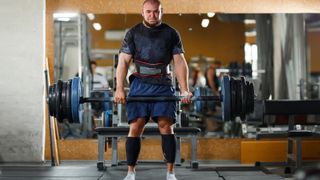 Man deadlifting heavy weights in the gym using an axle barbell