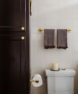 bathroom with white tiled walls, dark brown cabinet and gold hardware