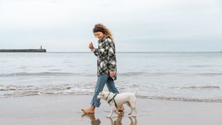 Woman walking on beach with her dog