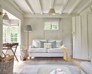 white painted beamed living room in a country cottage with neutral sofa