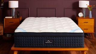 The DreamCloud Premier Mattress on a wooden bedframe in a deep red color bedroom