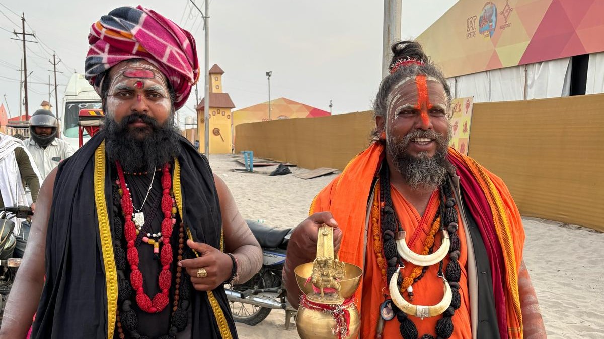 Two Indian men in robes and necklaces, with face paint, at the Kumbh Mela