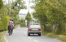 Horses riding down a country B road with a range rover driving past