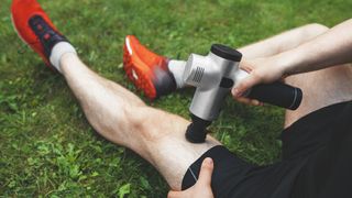 Man uses a massage gun on his legs