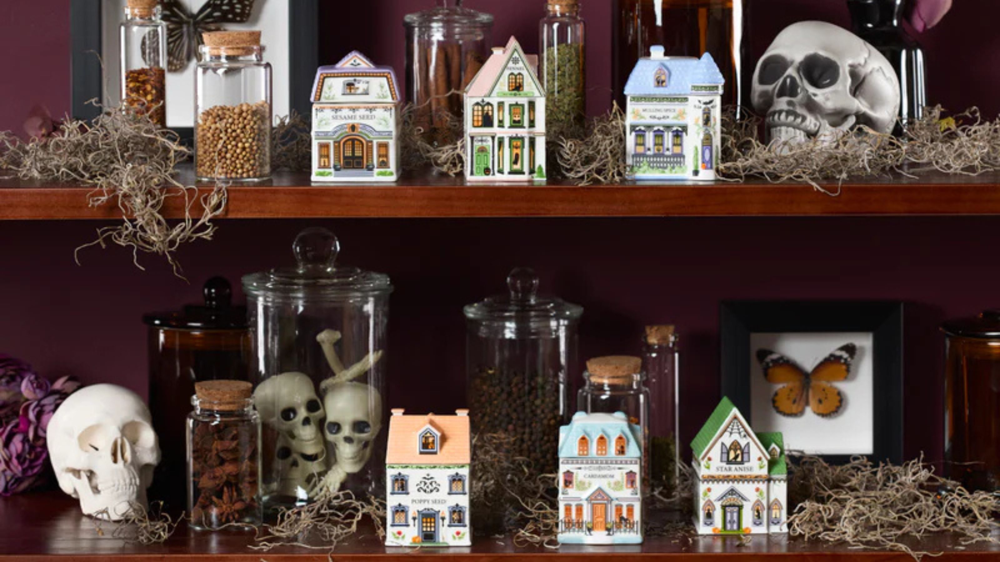 Lenox Halloween spice village on shelves decorated with spooky decor including fake skulls and dried moss. 