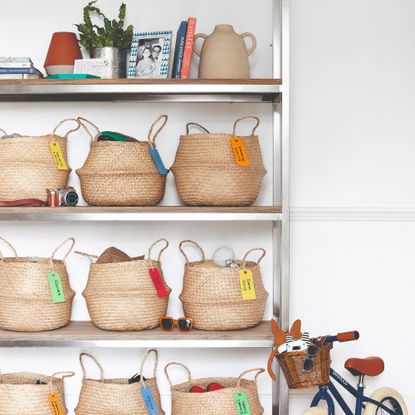 Open shelving with labelled storage baskets and a child's bike leaned against it