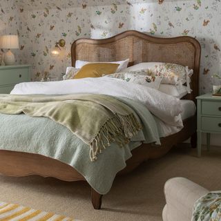 Country-style bedroom with brown rattan French-style bedframe and layered blankets and throws