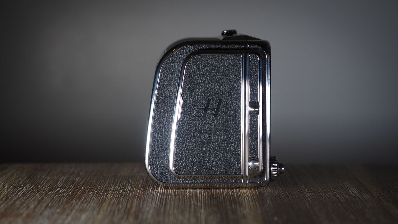 The Hasselblad 907X &amp; CFV 100C medium format camera with digital back, on a wooden table with artistic lighting