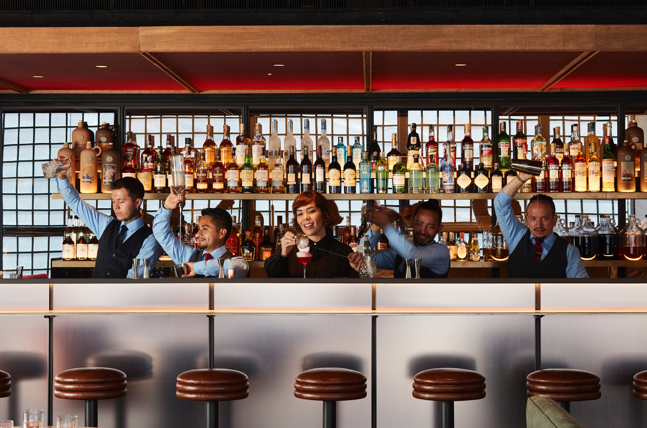 Bartenders lined up behind a bar
