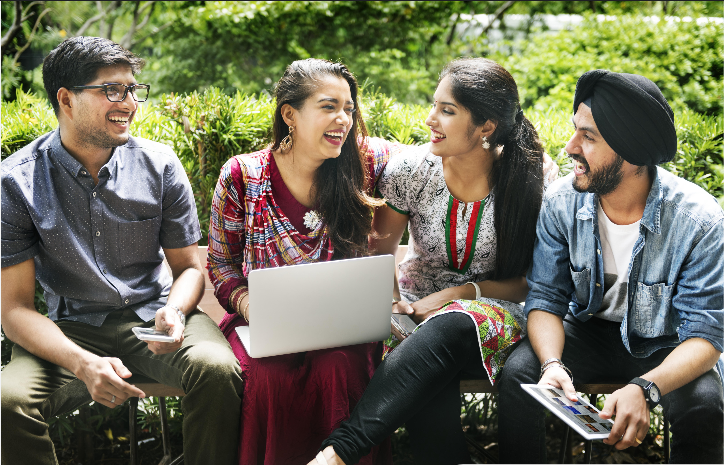 A group of students talking around a laptop