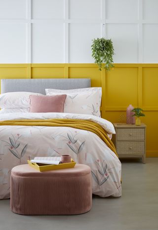 yellow bedroom with pink bedding, grey headboard and panelled walls