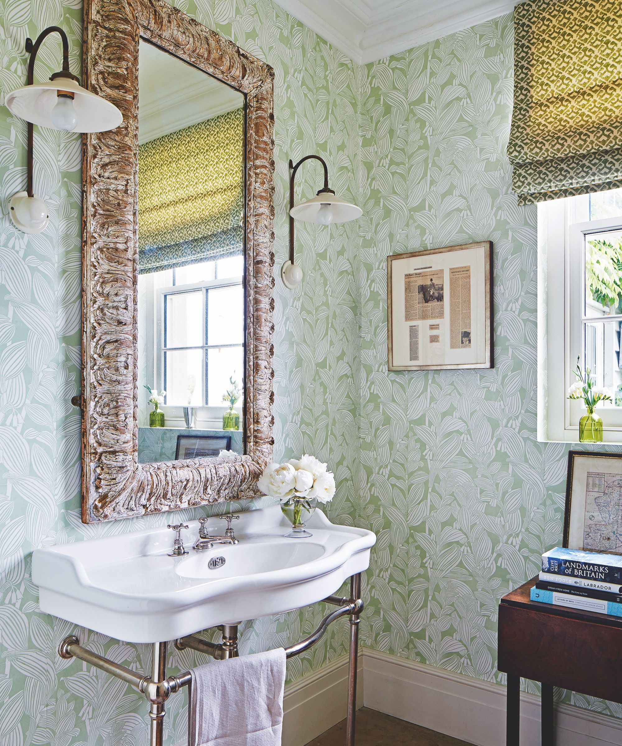 Vintage bathroom with wallpapered green walls, vintage china sink, large decorative mirror and wall sconces