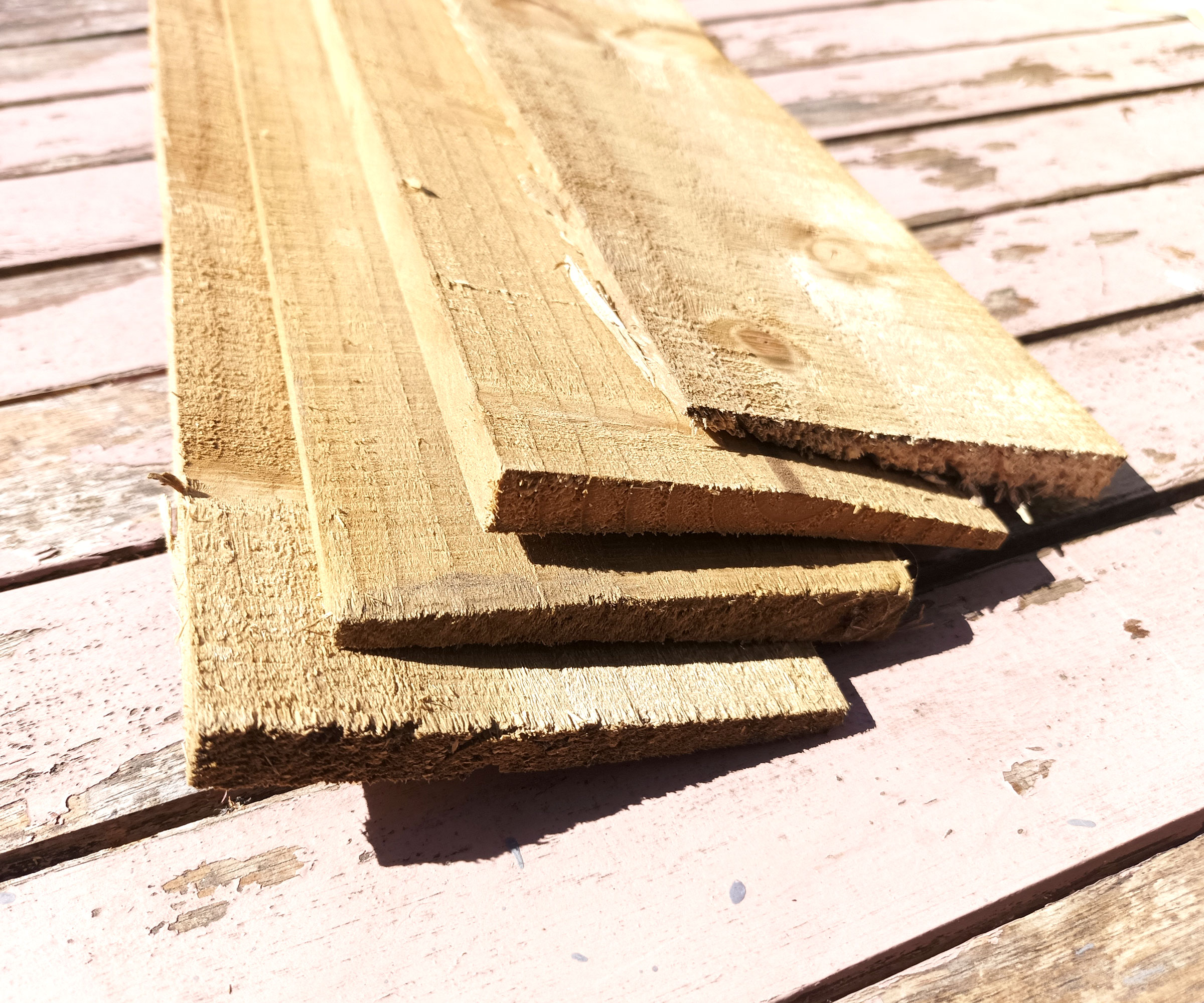 End of timber feather edge boards on light pink worn wooden table