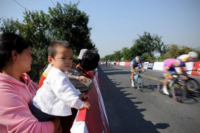 A family watch cyclists during the first stage of the 2013 Tour of Beijing