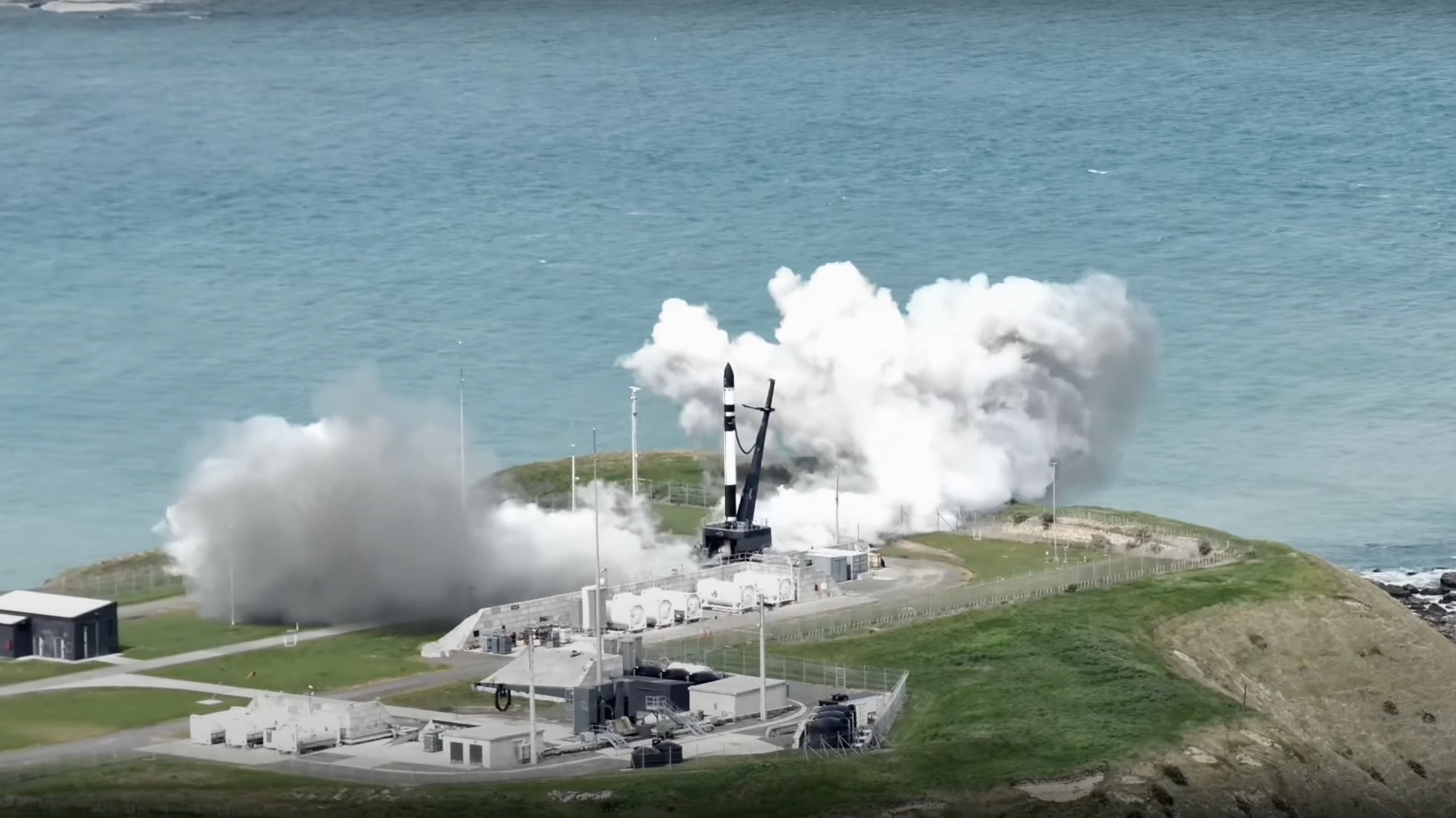 Science and Nature news a black and white rocket stands on a seaside launch pad with smoke billowing around its base