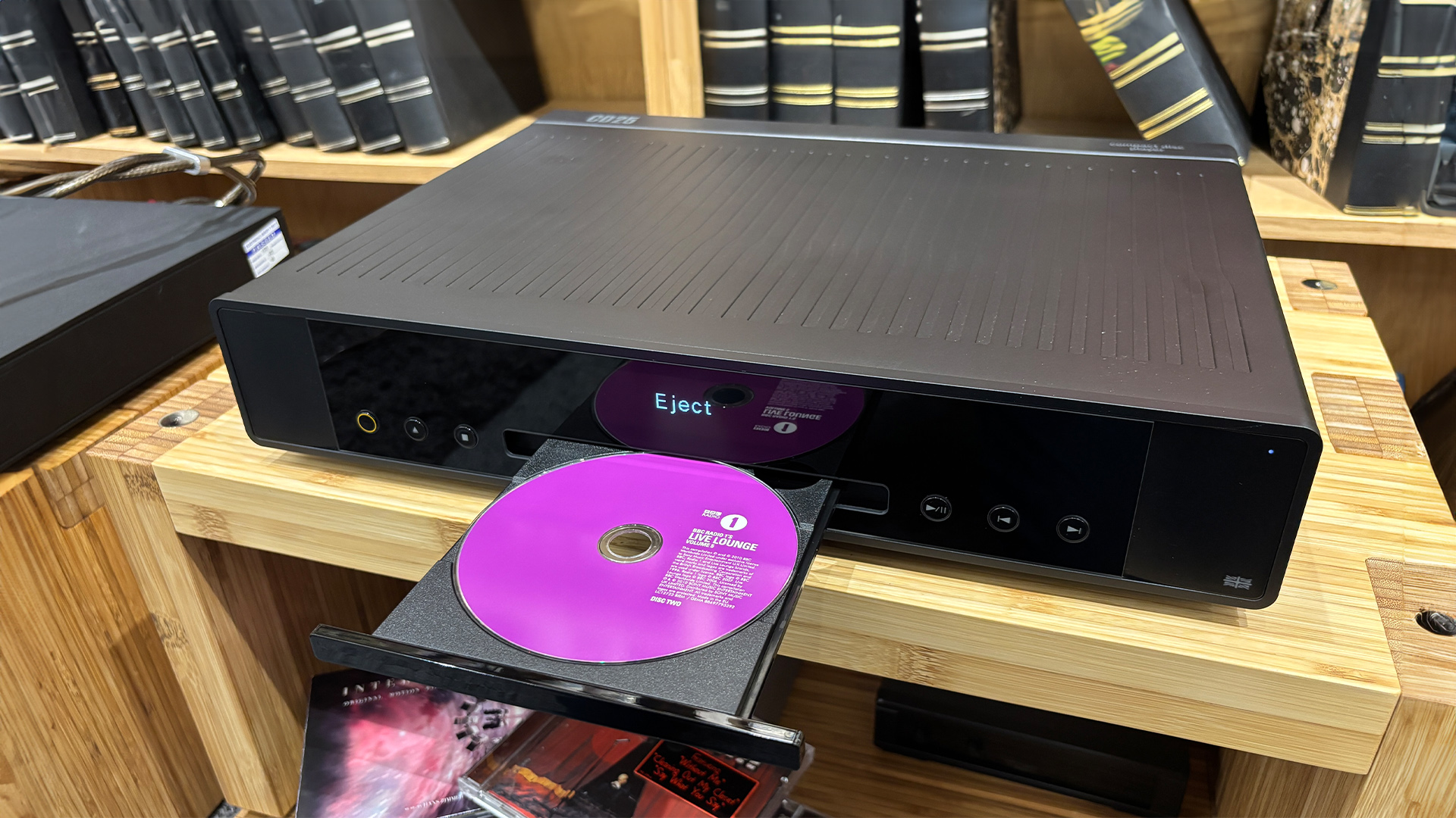Arcam CD25 CD player on wooden hi-fi rack, tray is out holding pink CD